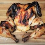 A whole grilled chicken that was marinaded for 24 Hours in a mojo marinade displayed on a wood cutting board