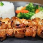 Grilled Asian Chicken Skewers with white rice and mixed vegetables in the background