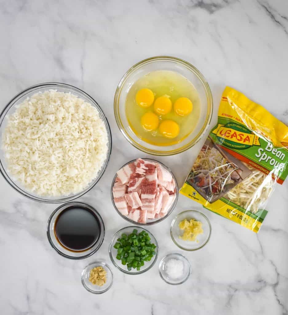 The prepped ingredients for the bacon fried rice arranged on a white table.