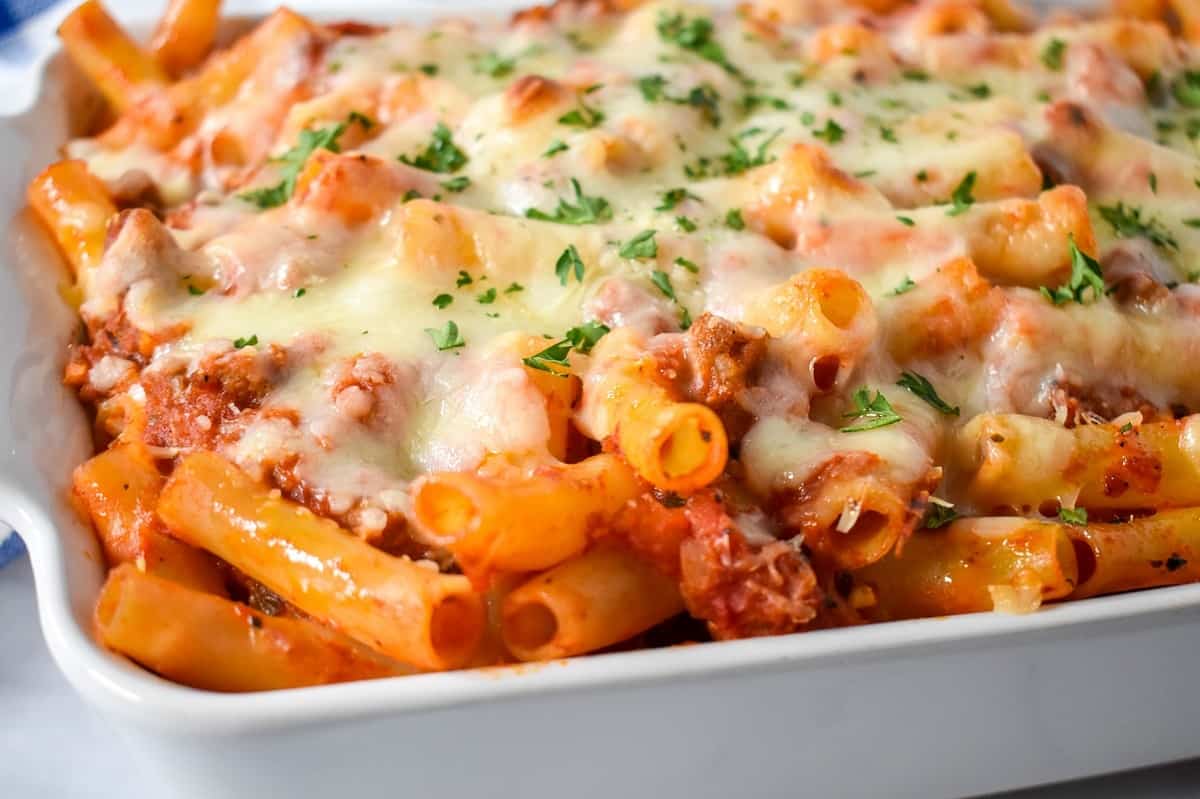 A close up of the baked ziti in a white casserole dish.