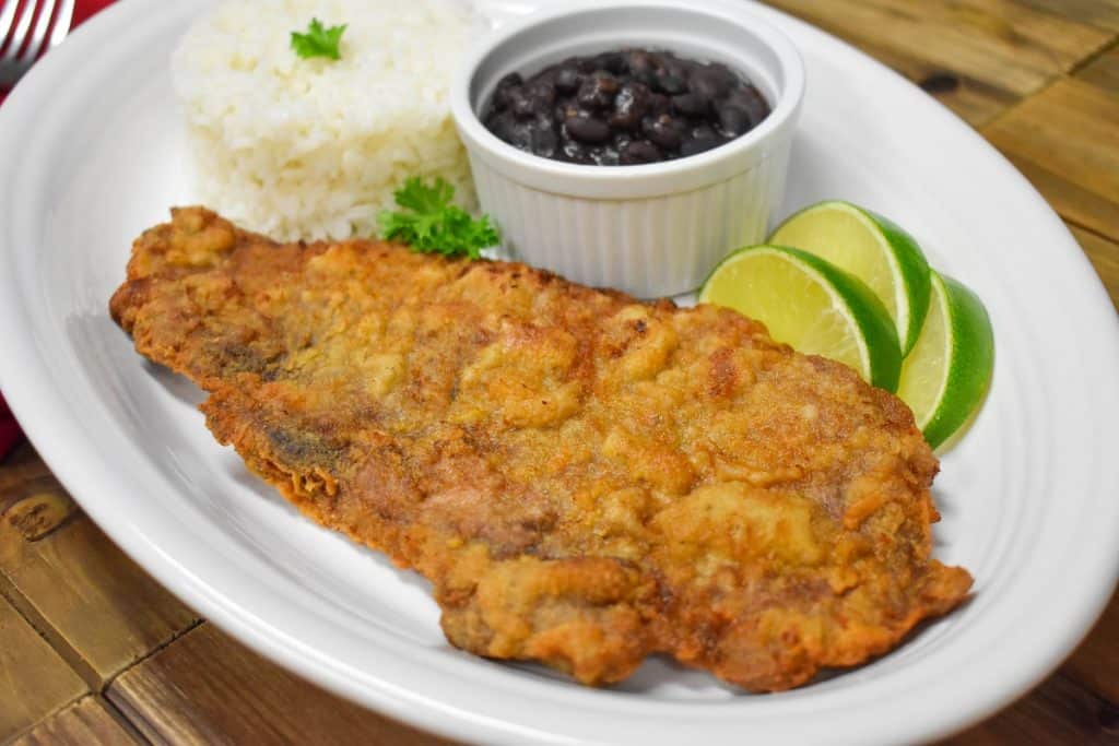 A large thin steak that coated in cracker meal and fried until golden. Served on a large platter with rice, beans and lime wedges.