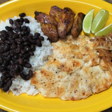 Thin chicken steak fried until golden served with rice, black beans and plantains