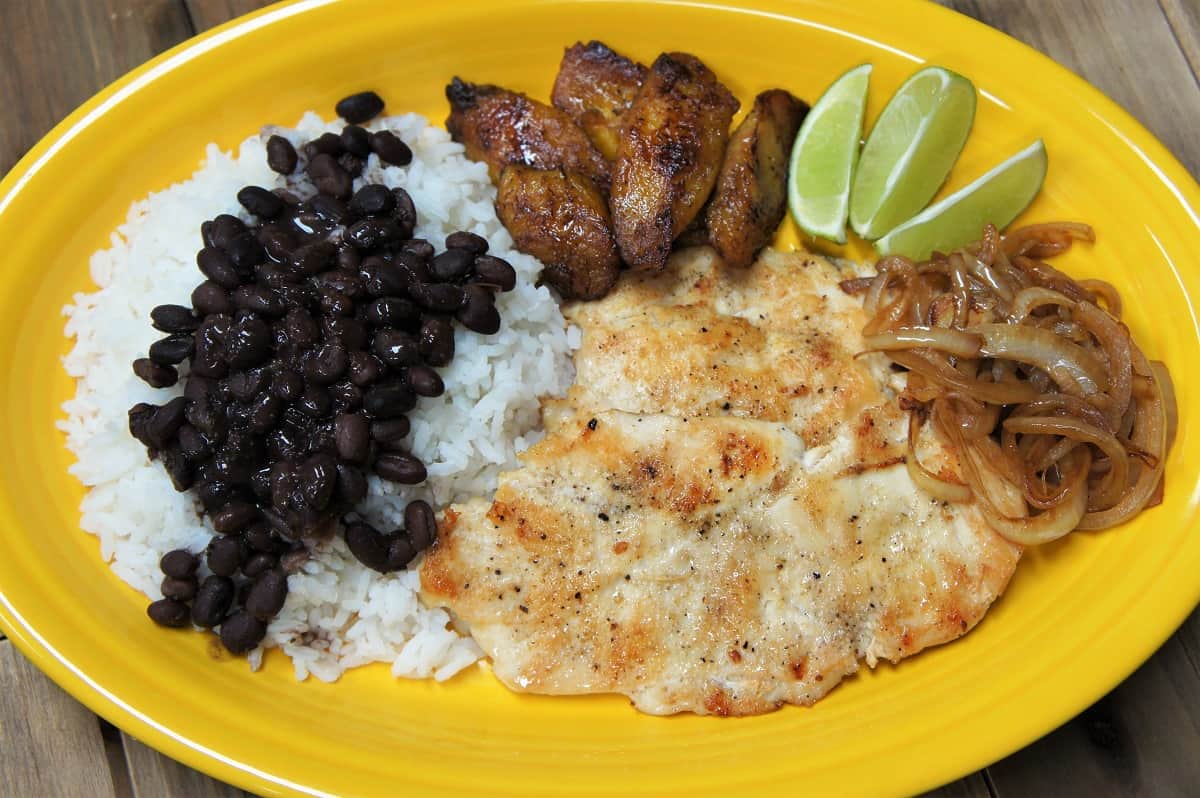 Thin chicken steak fried until golden served with rice, black beans and plantains
