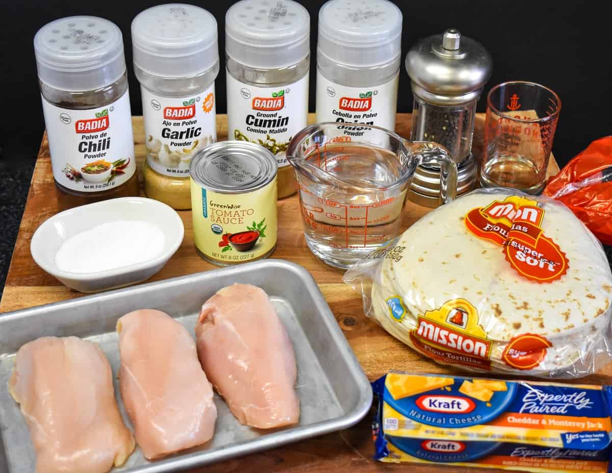 The ingredients for the chicken taquitos arranged on a wood cutting board.