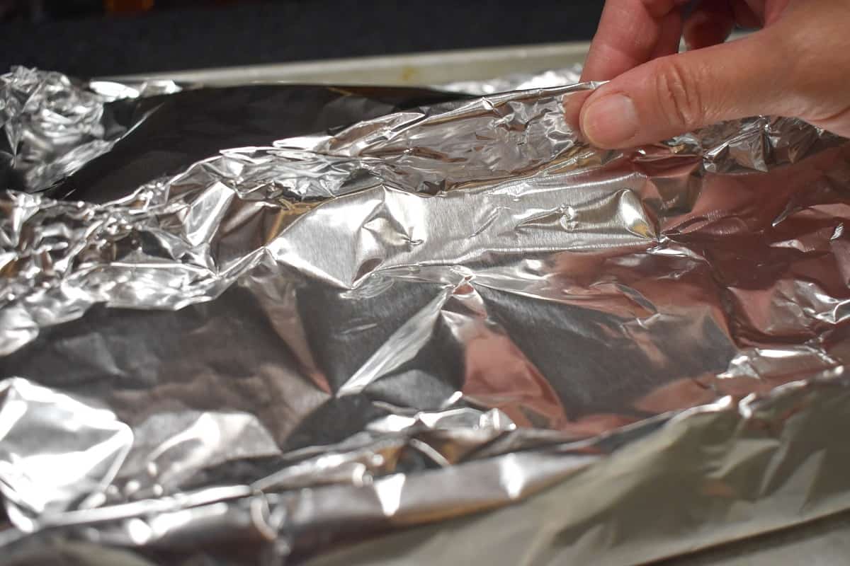 An image of fingers crimping closed an aluminum foil pack.