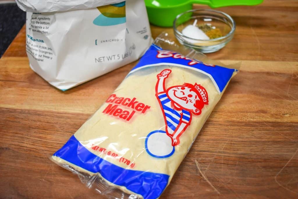 A packet of cracker meal displayed on a wood cutting board.