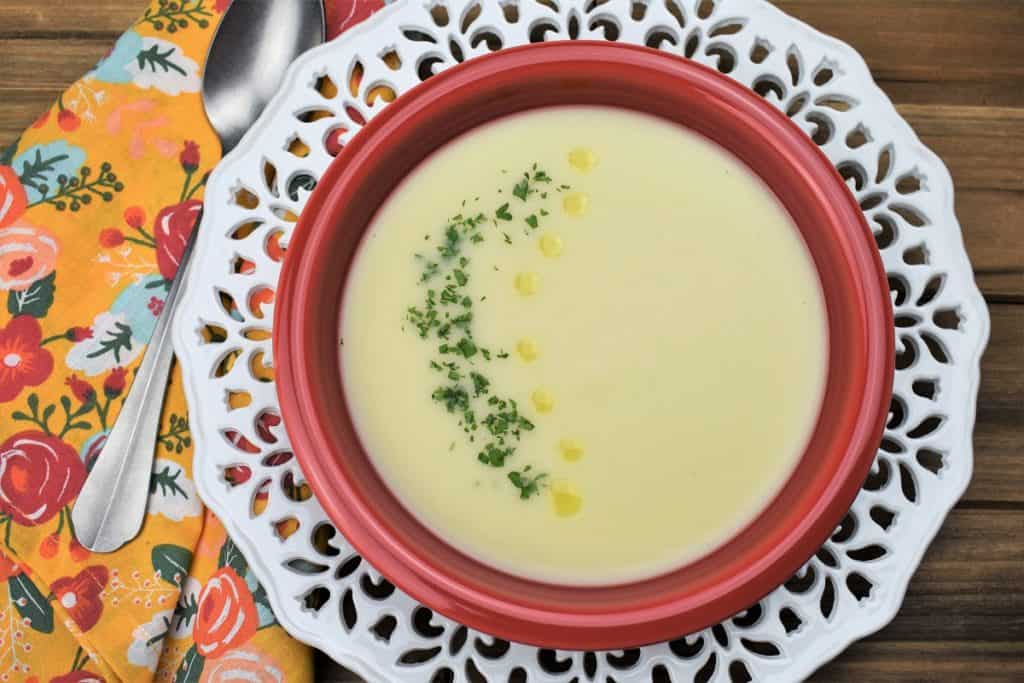 Crema de Malanga served in a red bowl and garnished with chopped parsley and drops of olive oil