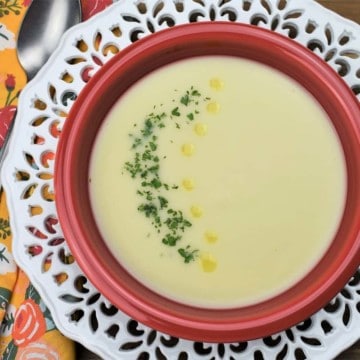 Crema de Malanga served in a red bowl and garnished with chopped parsley and drops of olive oil