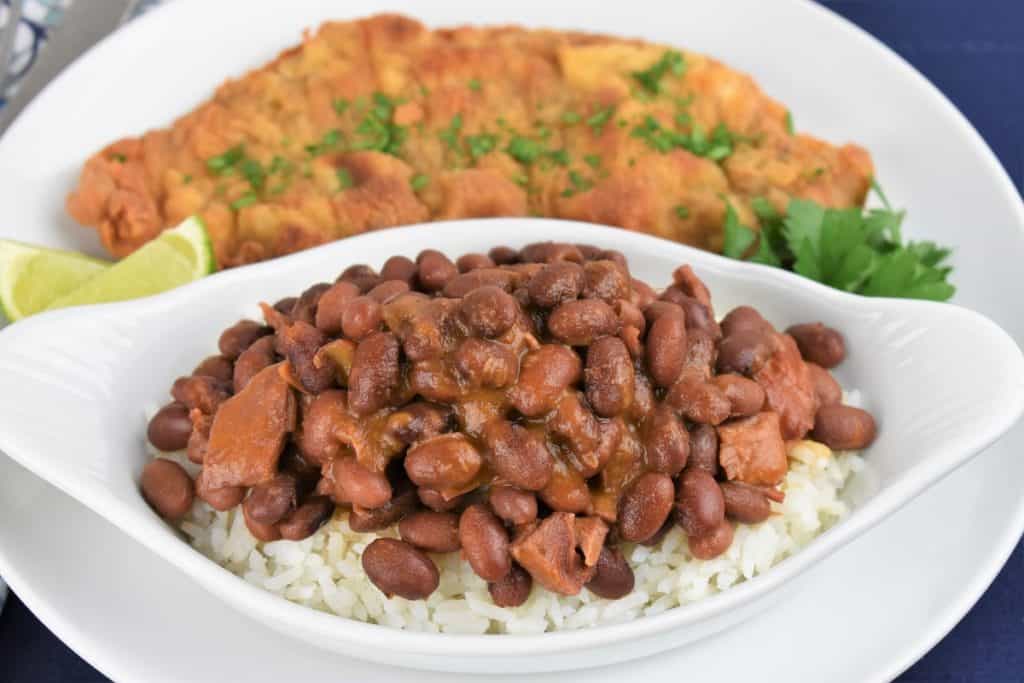 Cuban Style Red beans served over white rice with a breaded steak in the background