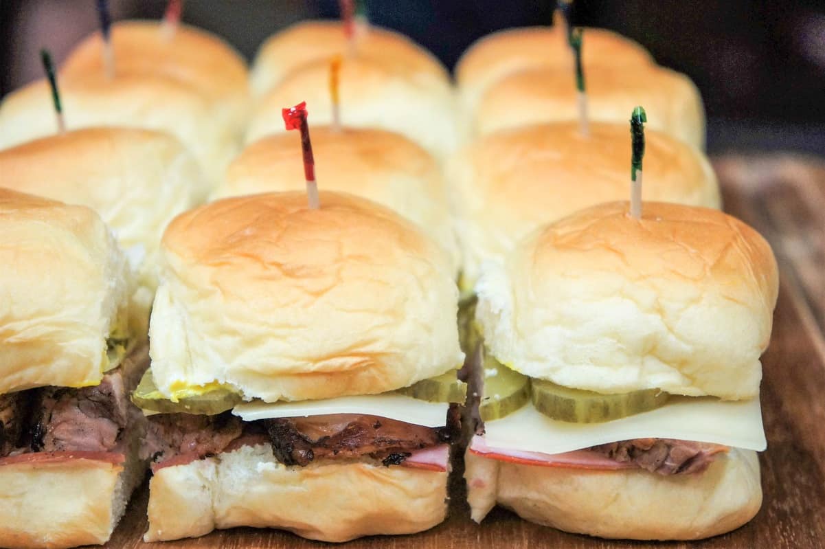 The sliders already cut but not separated displayed on a wood cutting board.