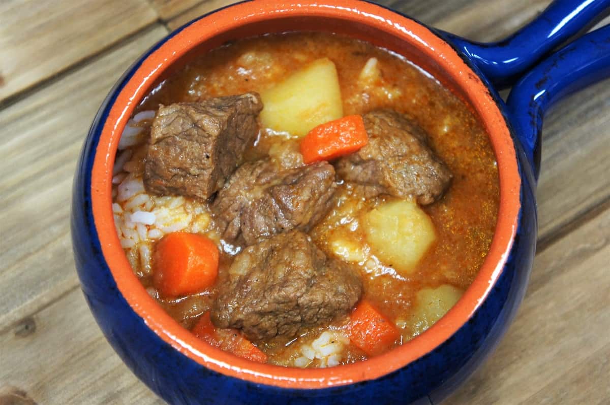 Cuban-Style Beef Soup a thick soup with beef, potatoes and carrots served in a blue crock.