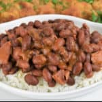 Cuban Style Red Beans served over white rice and a fried pork steak in the background.