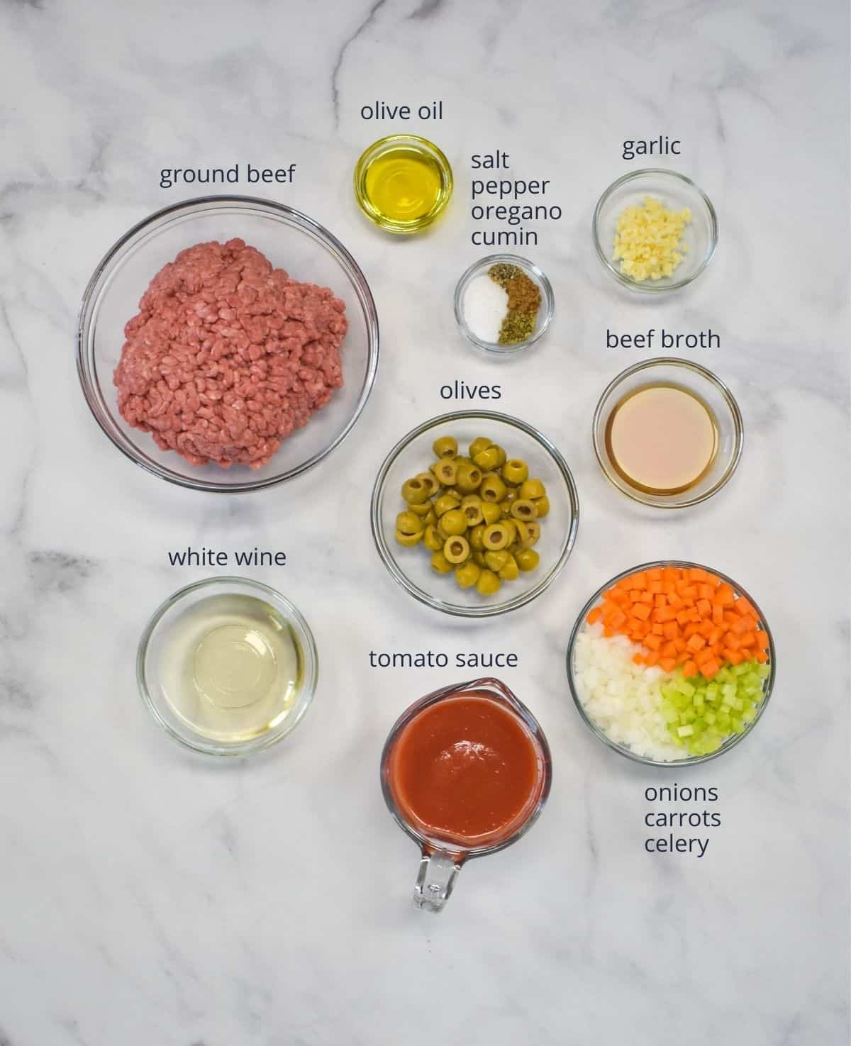 The ingredients arranged in separate bowls on a white table. Each ingredient is labeled with small black letters.