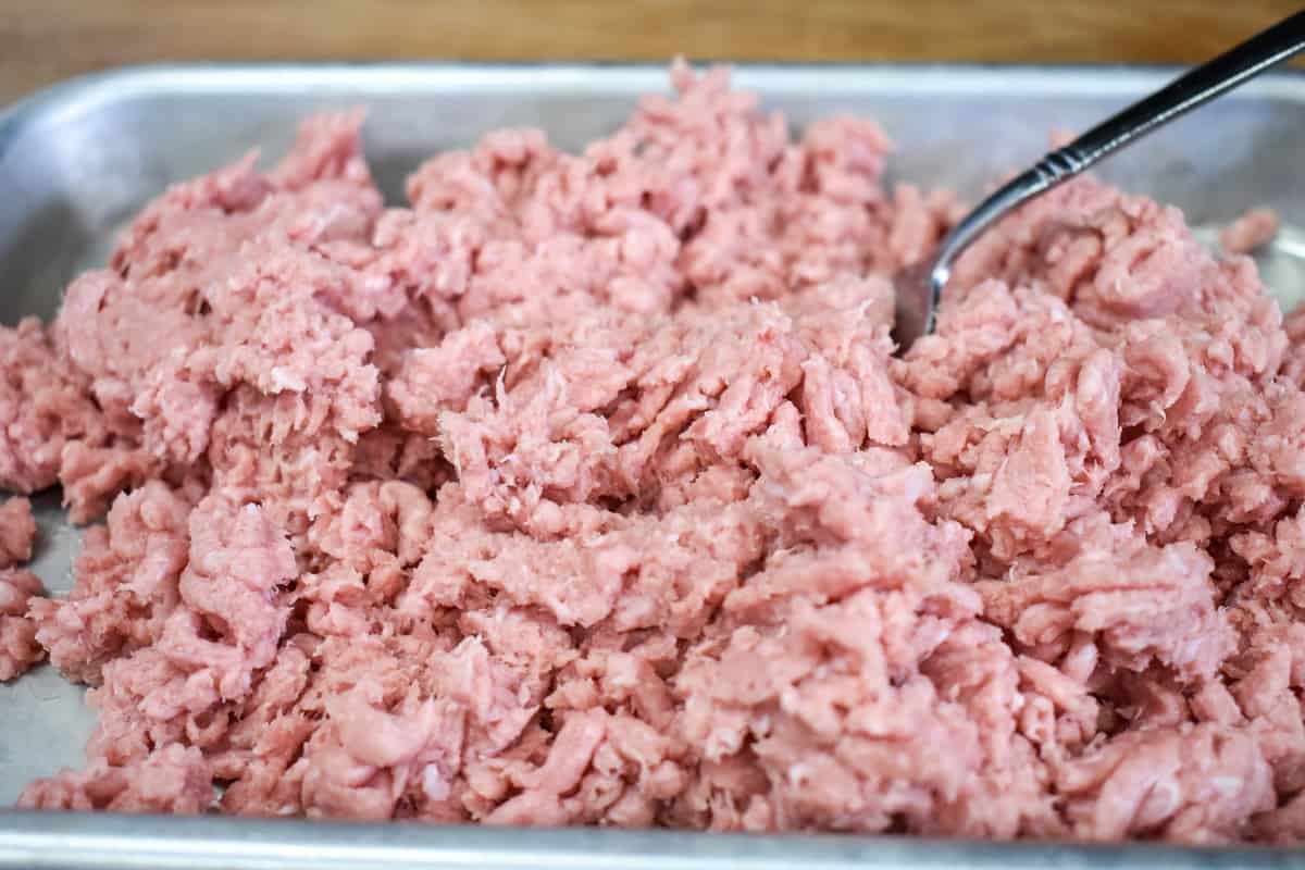 Uncooked ground turkey that has been stirred with a fork.