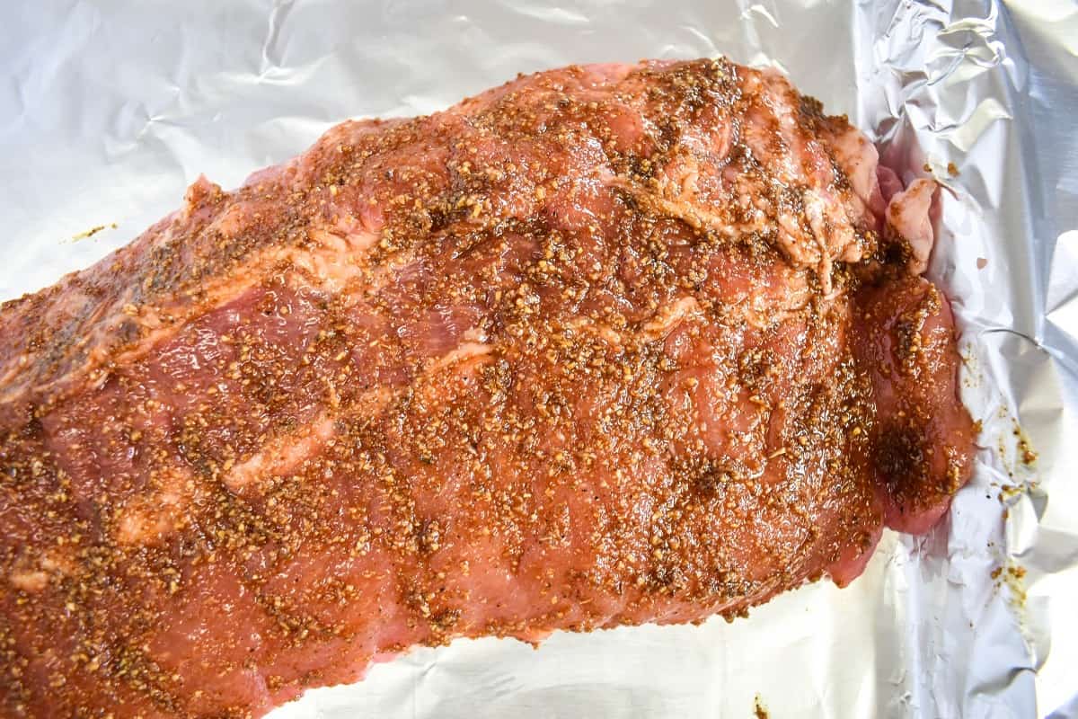A close up of the seasoned ribs on a foil lined baking sheet.