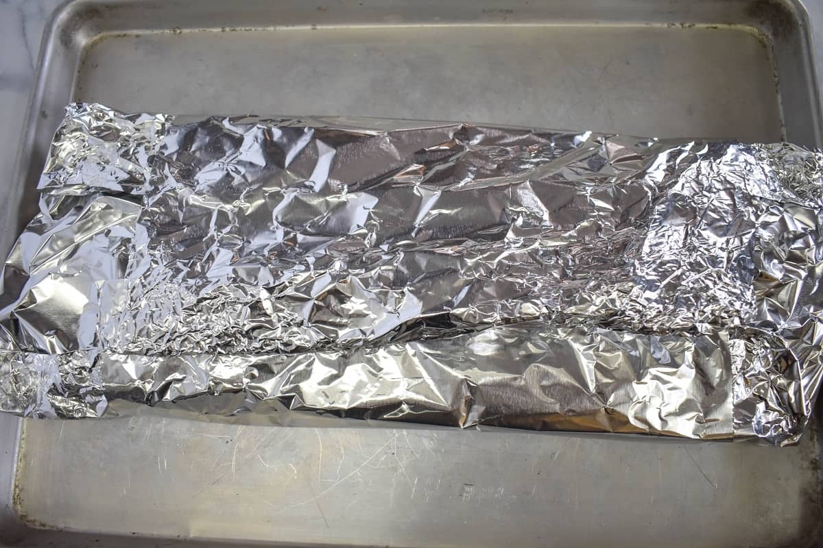 The foil packet closed up set on a baking sheet.