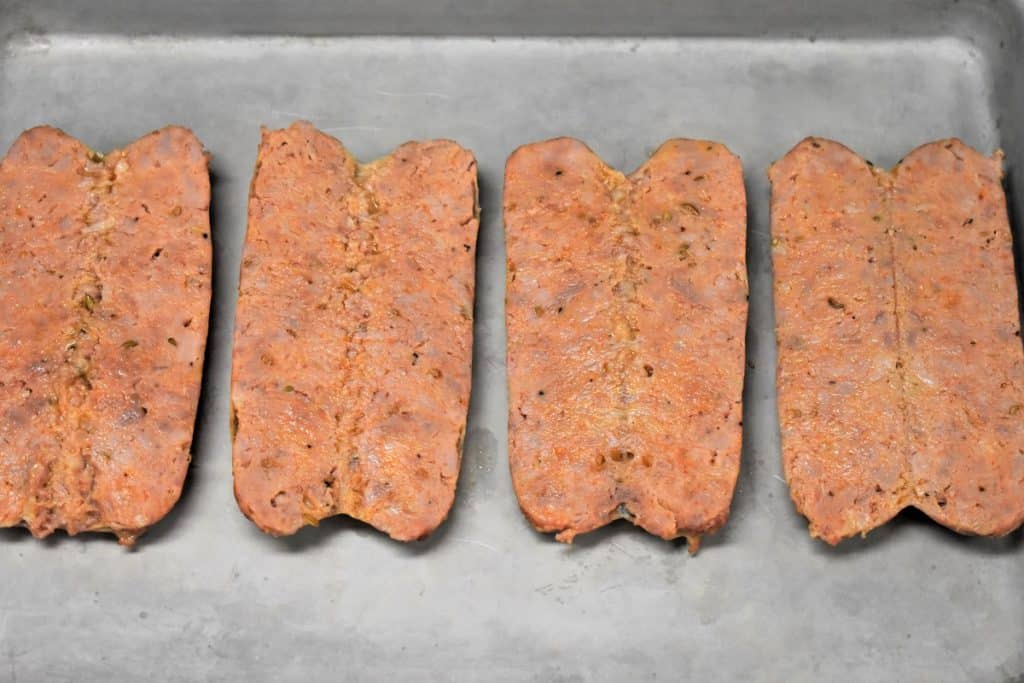 Four Italian Sausages butterflied on a metal baking sheet