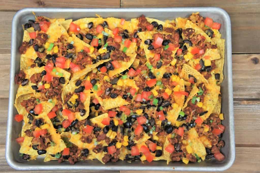 Loaded Sheet Pan Nachos topped with ground turkey, melted cheese, black beans, corn and diced tomatoes