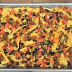 Loaded Sheet Pan Nachos topped with ground turkey, melted cheese, black beans, corn and diced tomatoes