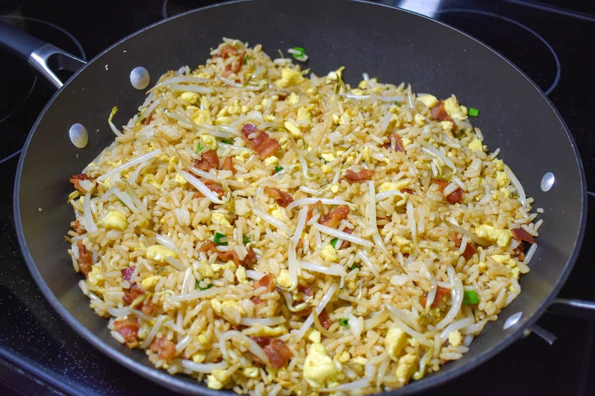 The completed bacon fried rice in a large, black skillet.