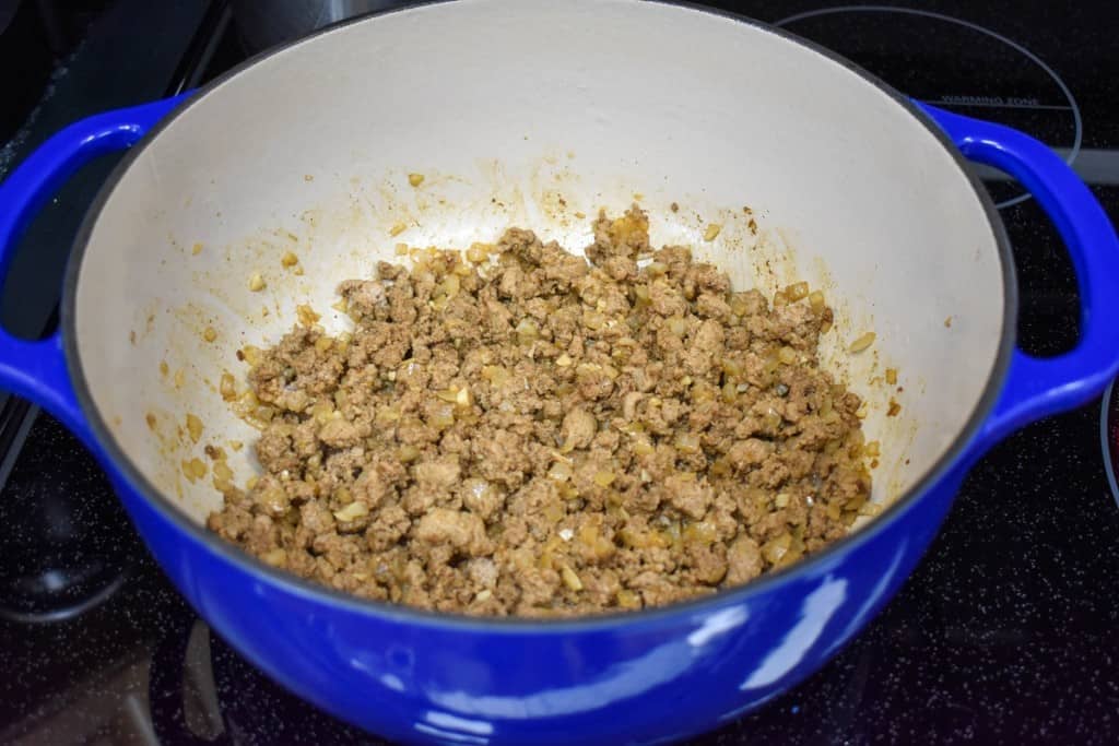 The browned ground turkey in a large blue pot with an off-white interior.