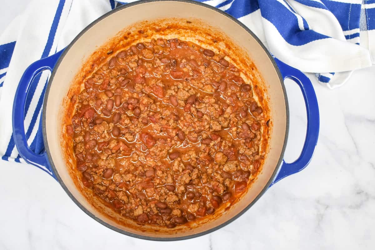 An image of the cooked chili, still in the blue pot with a blue and white linen on a white table.