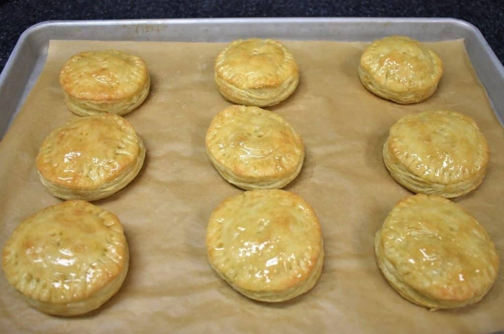Pastelitos de Carne Baked and Glazed arranged on a baking sheet lined with parchment paper