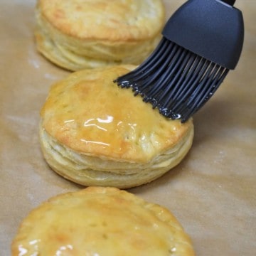 Pastelito de carne being glazed with honey with a gray pastry brush