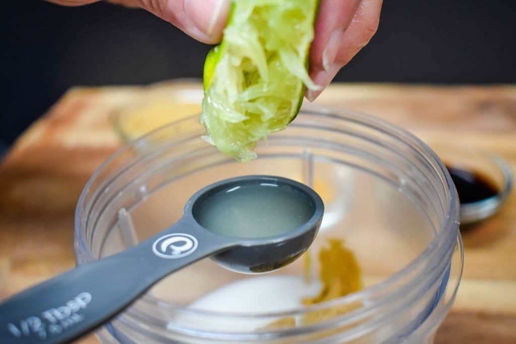 A half a lime being juiced into a spoon.