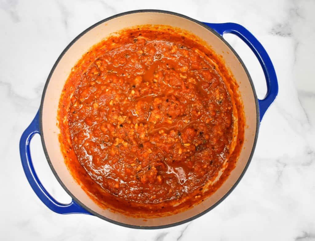 The finished Italian sausage sauce still in the pot set on a white table.