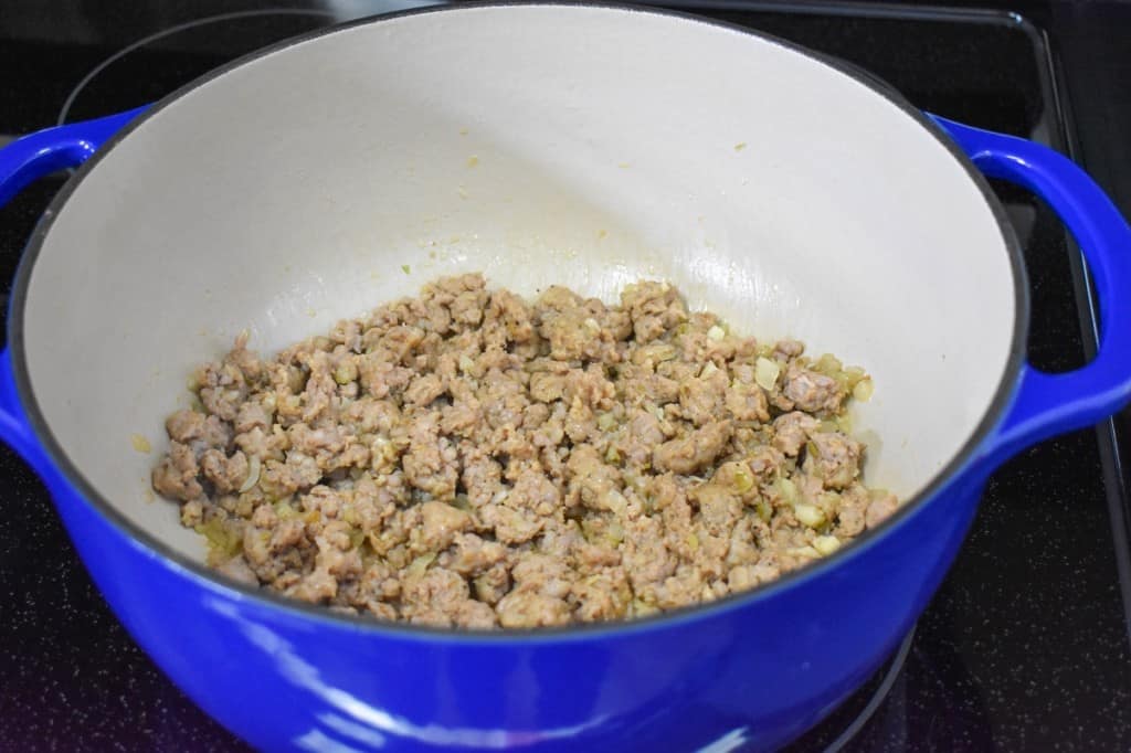 Browned sausage in a large blue pot.