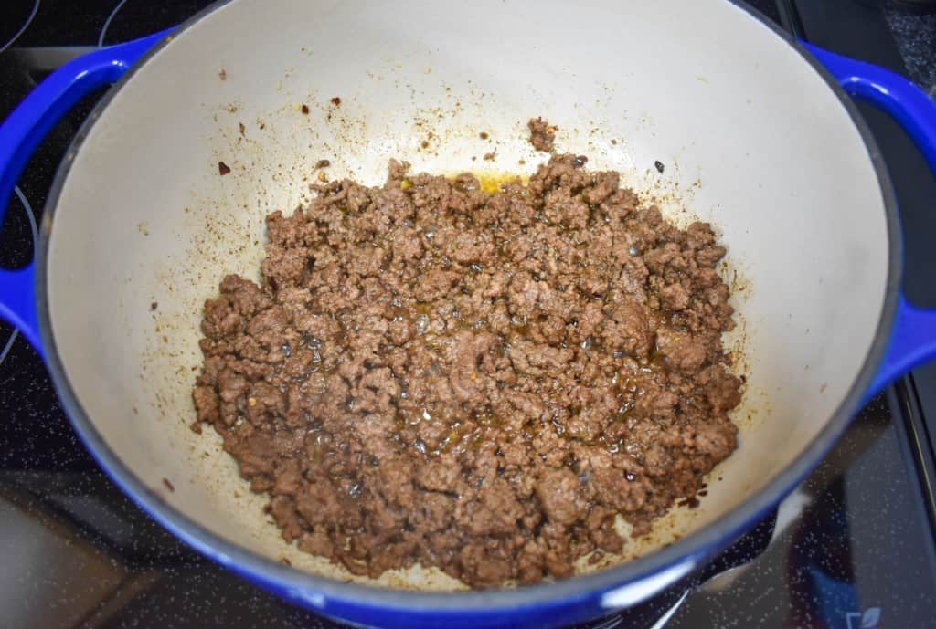 Browned ground beef in a blue pot with white inside.