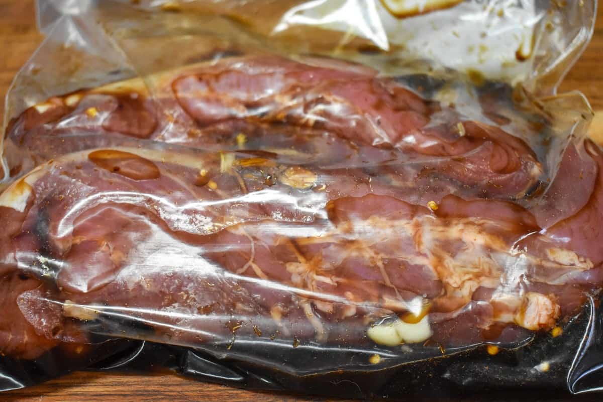 Two pork tenderloins in a plastic re-sealable bag with the Asian marinade.