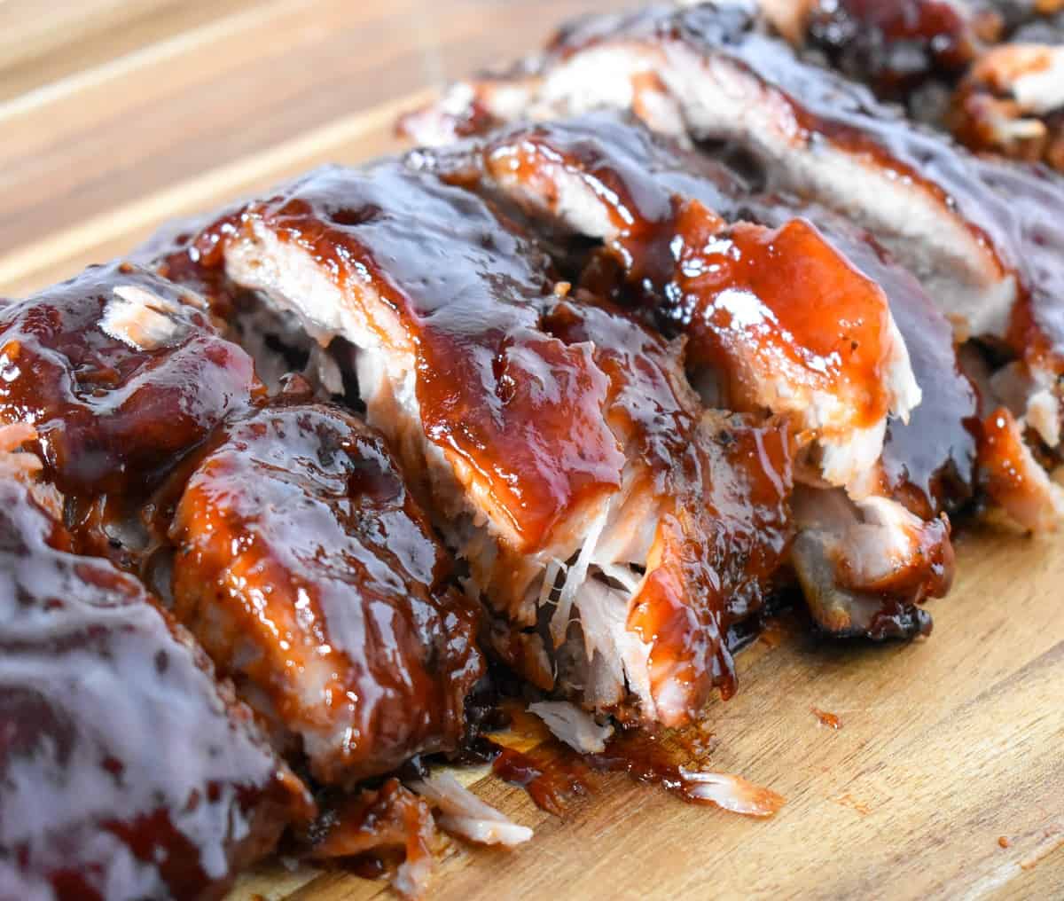 The finished oven barbecue ribs cut on a wood cutting board.