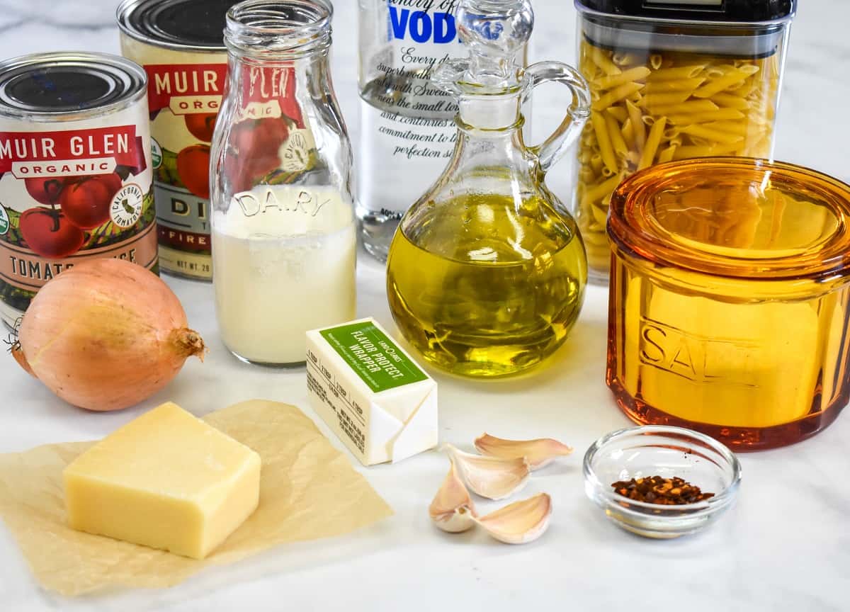 The ingredients for the pasta with vodka sauce, before prepping, arranged on a white table.