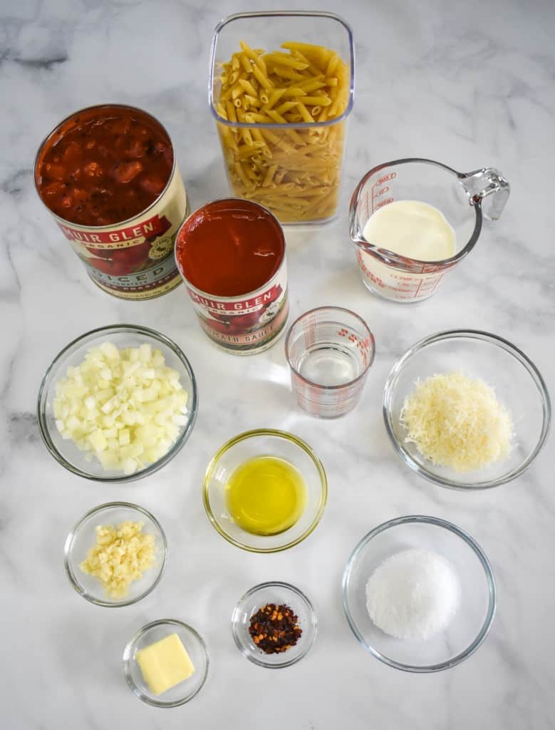 The prepped ingredients separated in clear bowls and measuring cups and arranged on a white table.