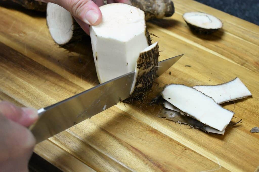 Peeling a Malanga on a wood cutting board