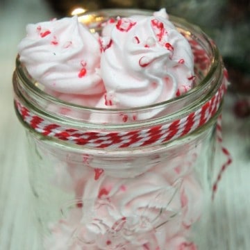 Peppermint Meringue Cookies displayed in a clear mason jar with decorative ribbon