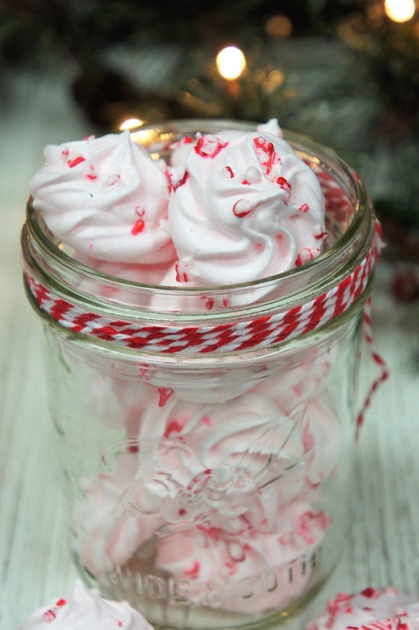Peppermint Meringue Cookies displayed in a clear mason jar with decorative ribbon