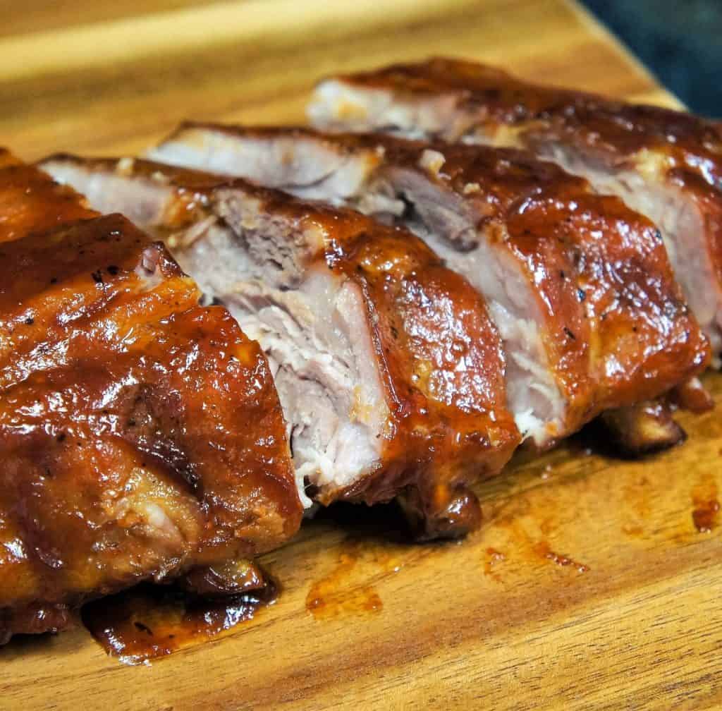 Pineapple habanero ribs, sliced on a wood cutting board.