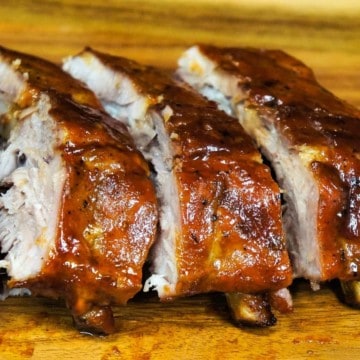 Pineapple habanero ribs sliced and arranged on a wood cutting board.