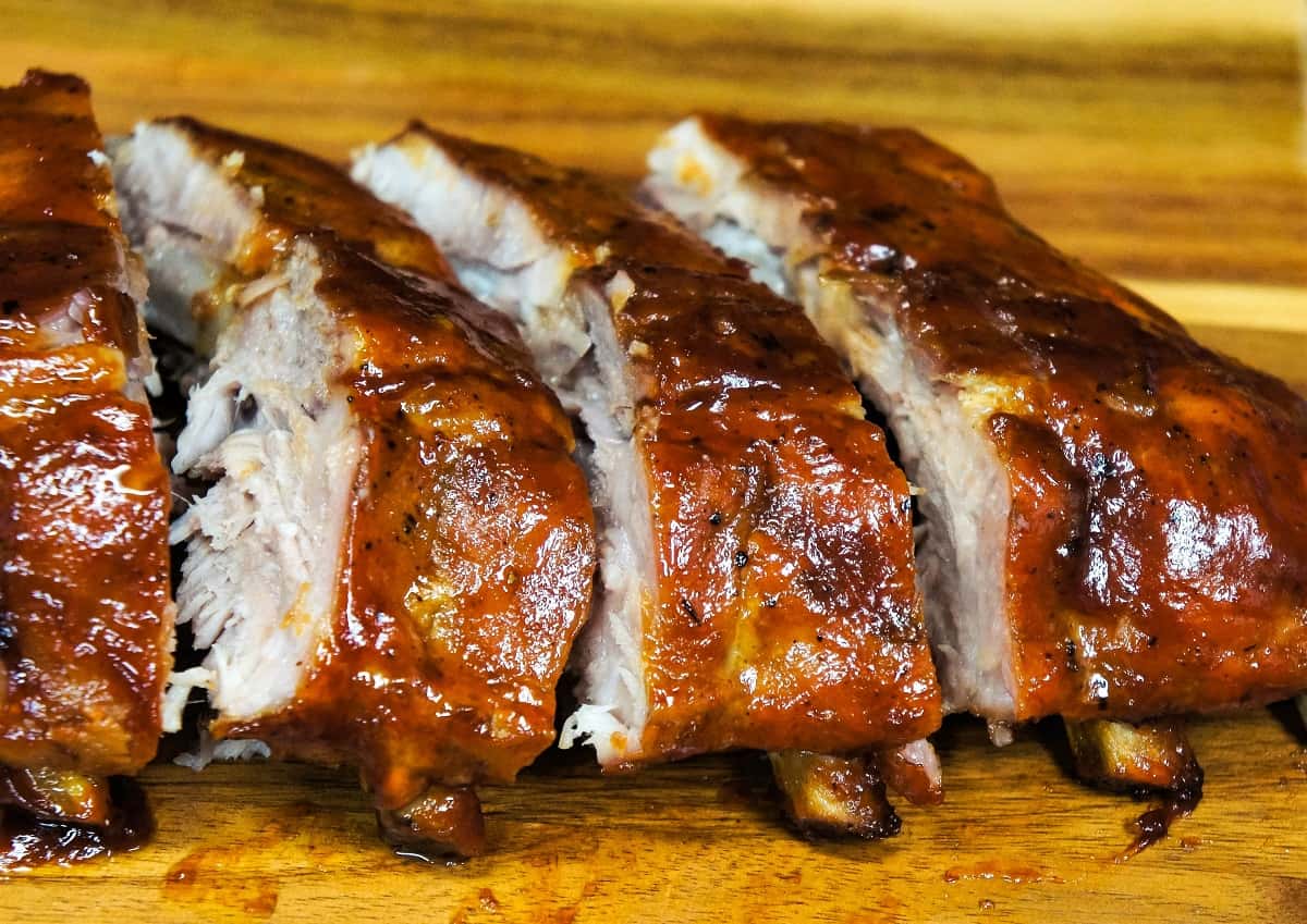 Pineapple habanero ribs sliced and arranged on a wood cutting board.