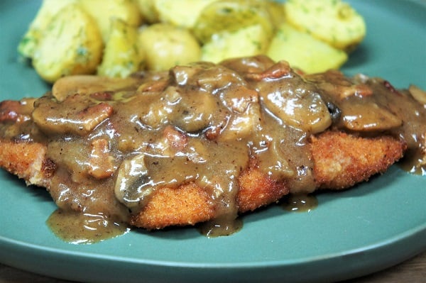 Pork Schnitzel & Mushroom Gravy with a side of boiled small potatoes served on a green plate