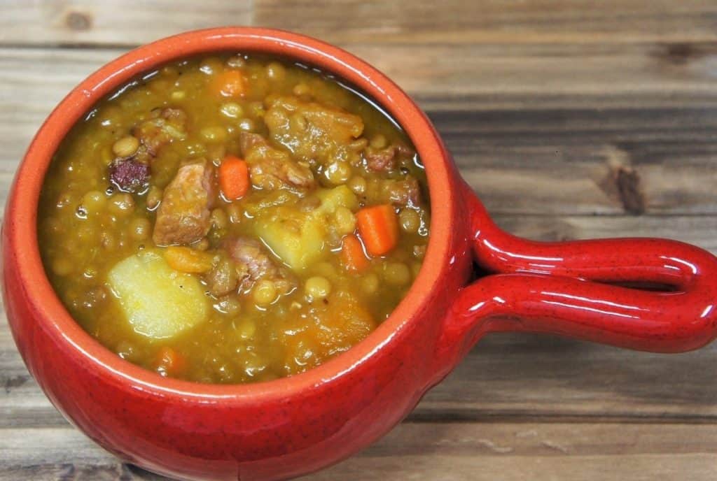 Potaje de Lentejas, lentil stew with potatoes, pork carrots, pumpkin served in a red crock