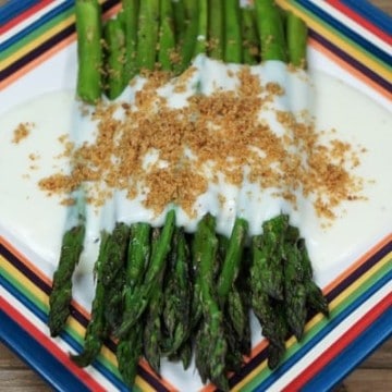 Roasted Asparagus, topped with mornay sauce and golden, breadcrumbs served on a multi-color plate