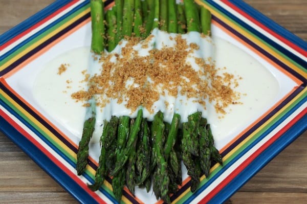 Roasted Asparagus, topped with mornay sauce and golden, breadcrumbs served on a multi-color plate