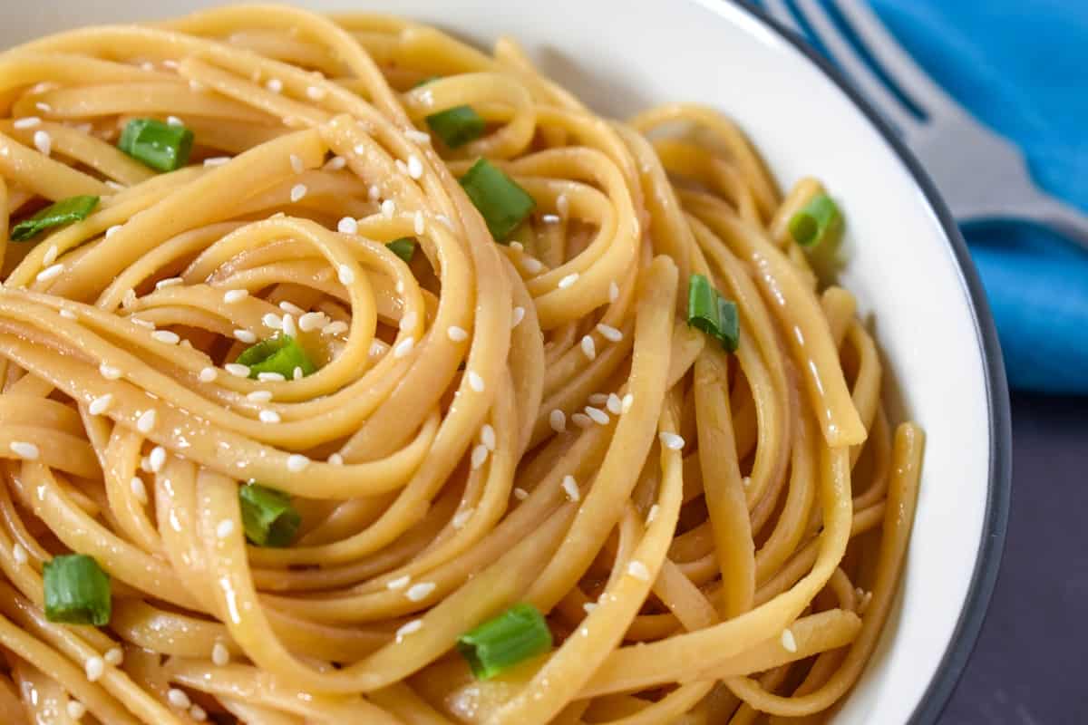 A close up of the noodles, garnished with sliced green onions and sesame seeds.