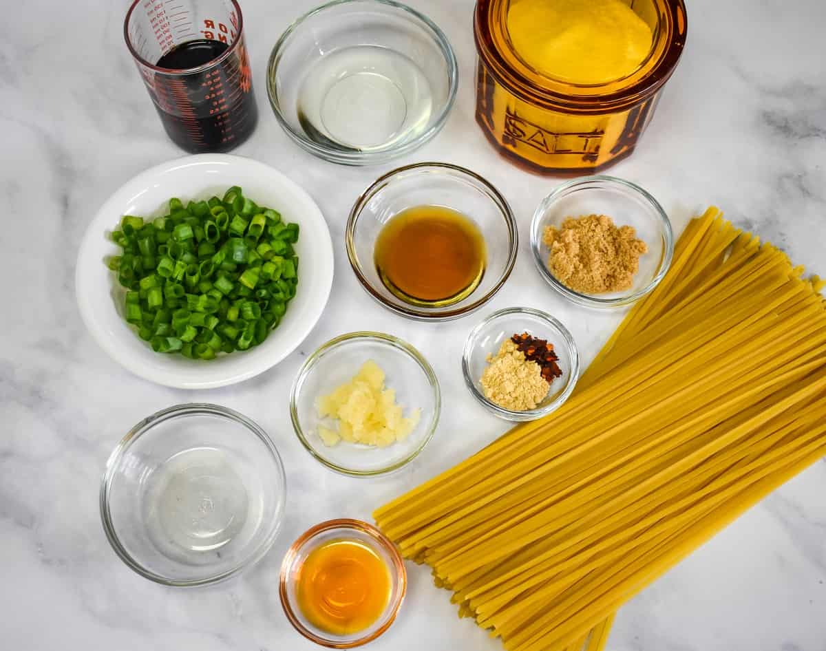 The prepped ingredients for the sesame noodles arranged on a white table.