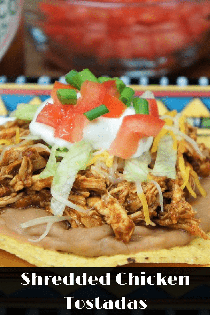 These shredded chicken tostadas are a great way to change up taco night. Here, chicken breasts are cooked in a tomato sauce flavored with a southwestern spice blend. Then the chicken is shredded and added back to absorb all the delicious sauce. The shredded chicken is served on crispy, corn tostadas with refried beans. #shreddedchickentostadas #tostadas #chicken #Mexicanfood #southwestern #partyfood