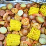 Sausage, shrimp, corn and potatoes in an open aluminum foil pack.